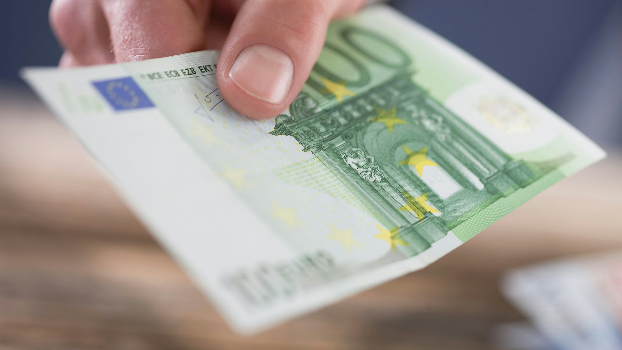 Eine Person hält einen 100-Euro-Schein in der Hand