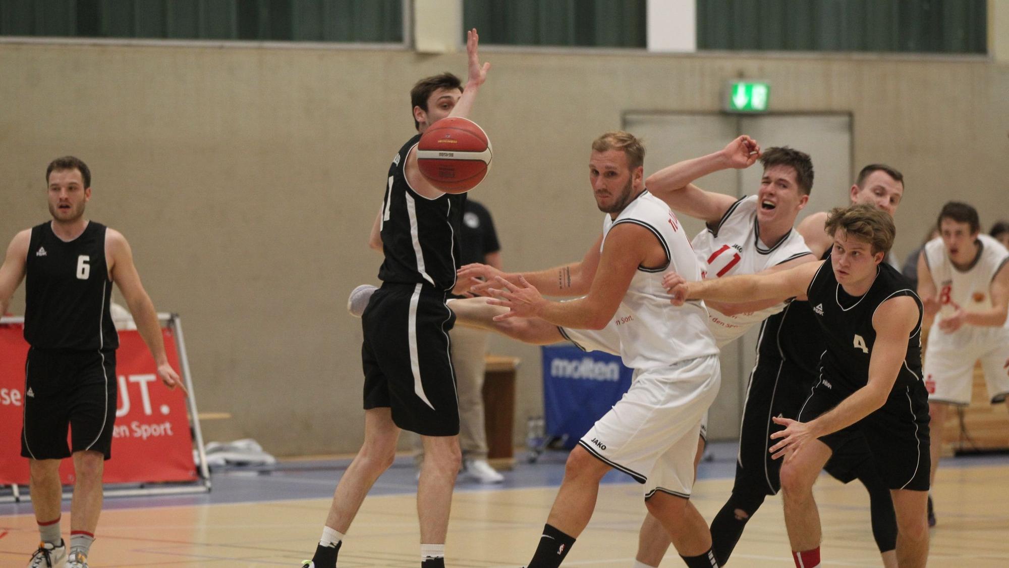 Im Basketball-Landesliga-Spiel gegen den TuS Brauweiler gerät Jan Philipp Thomas (Nr. 11) ins Straucheln. Vor ihm sein Mitspieler Christoph Gier. Der Ball ist weit weg, alle schauen ihm hinterher.