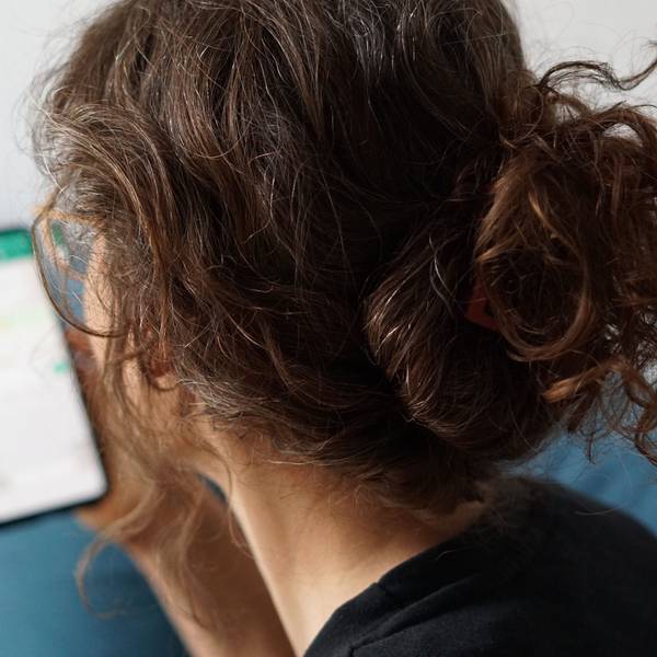 Eine junge Frau hält ihr Smartphone in der Hand und liest eine Whatsapp-Nachricht.