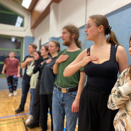 Die Schauspieler des Projekts „Spotlight Experience“ stehen in einer Reihe und halten ihr Hand auf die Brust