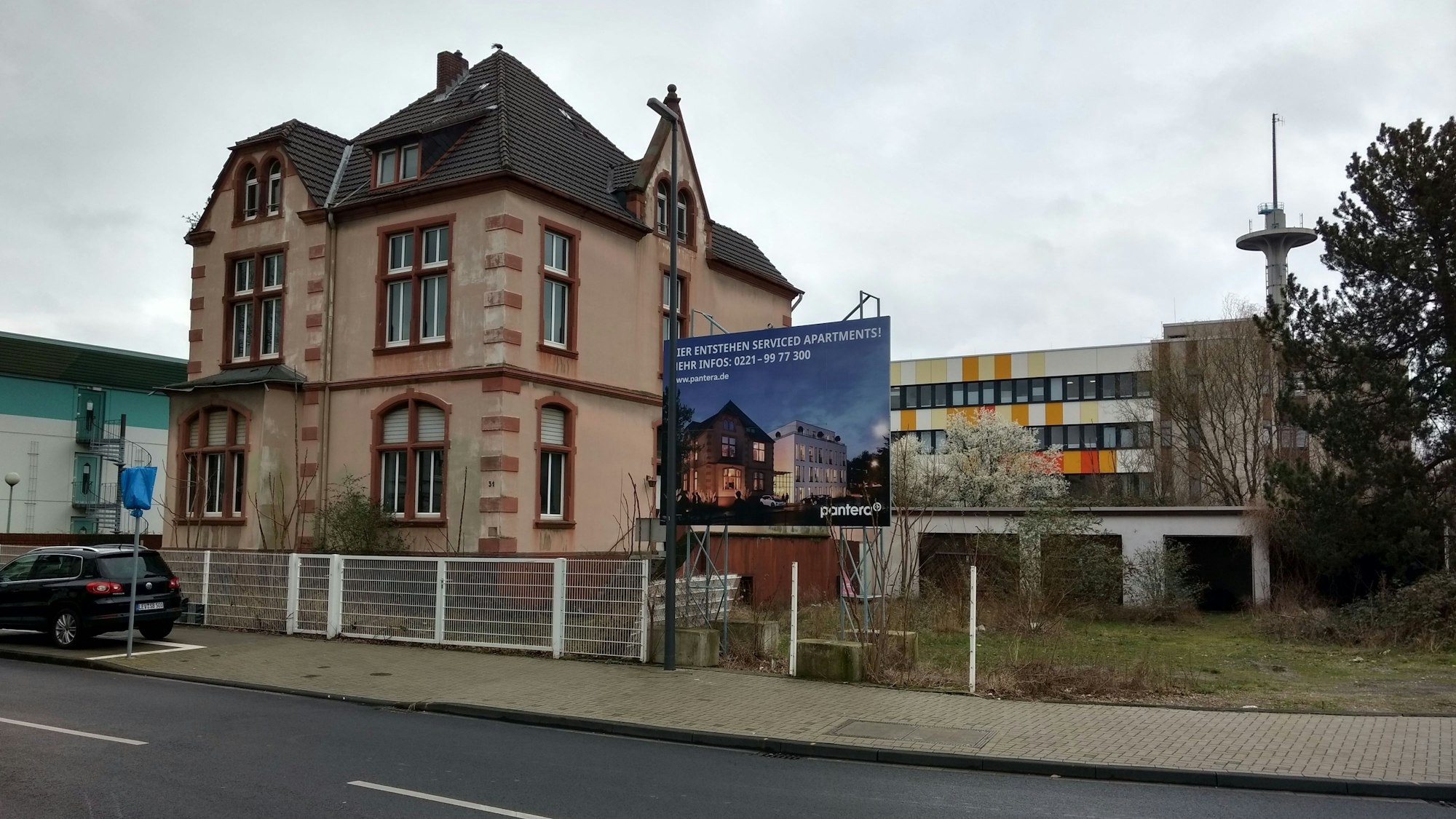 Ein Plakat kündigt neben einem alten Gebäude ein Bauprojekt an.