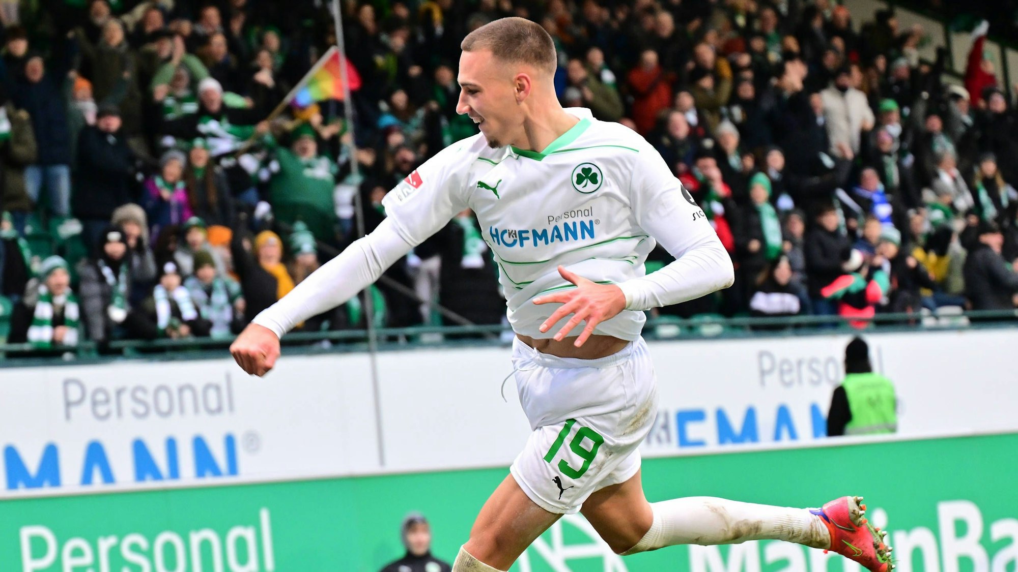 Ein Fußballspieler springt mit geballter Faust in die Höhe und freut sich über seinen Torerfolg.