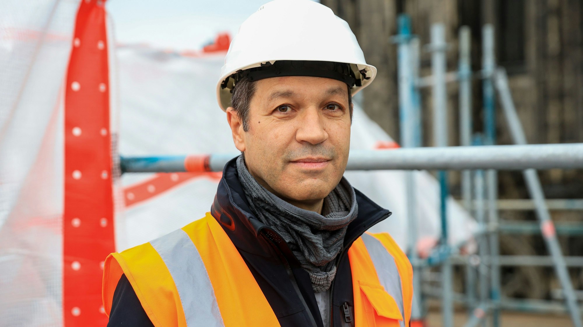 Das Bild zeigt einen Mann mit Bauhelm und Warnweste.