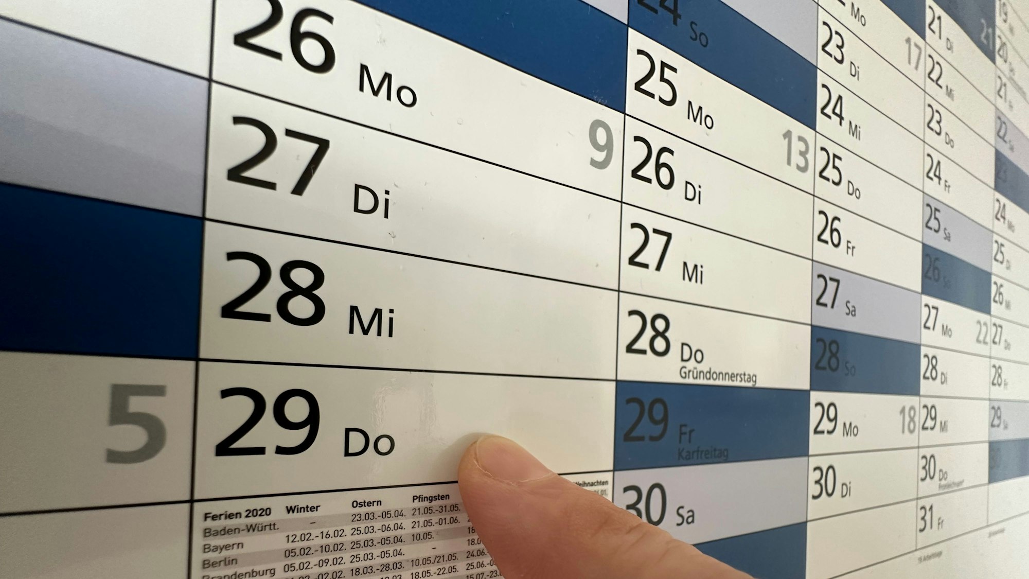 Ein Finger zeigt auf einen Kalender.