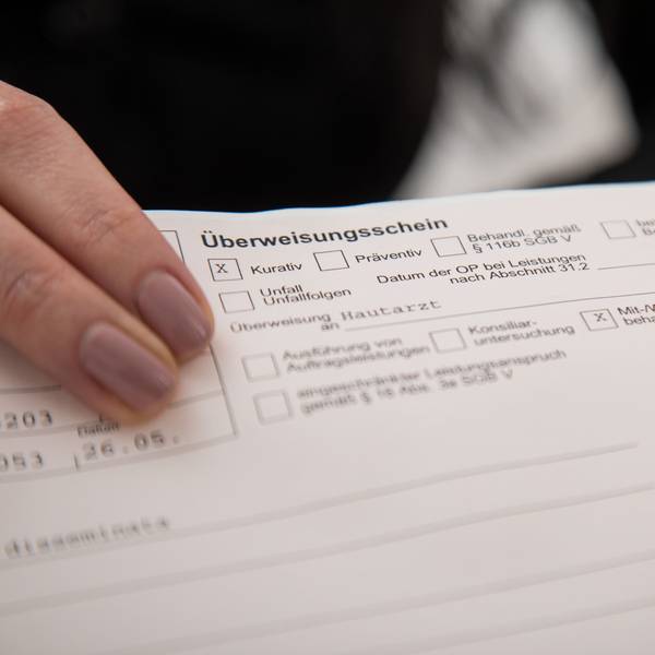 Zwei Finger zeigen auf einen Überweisungsschein.