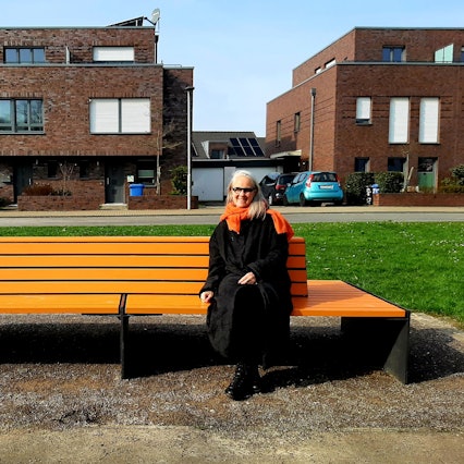 Susanne Wedewer vom Zonta-Club Leverkusen sitzt auf der vom Zonta-Club aufgestellten orangenen Bank in der Neuen Bahnstadt Opladen, auf der sie demnächst regelmäßig (bekannte) Menschen der Stadt zum Thema Frauenrechte, Gleichstellung, Sexismus, Gewalt gegen Frauen befragen will.
