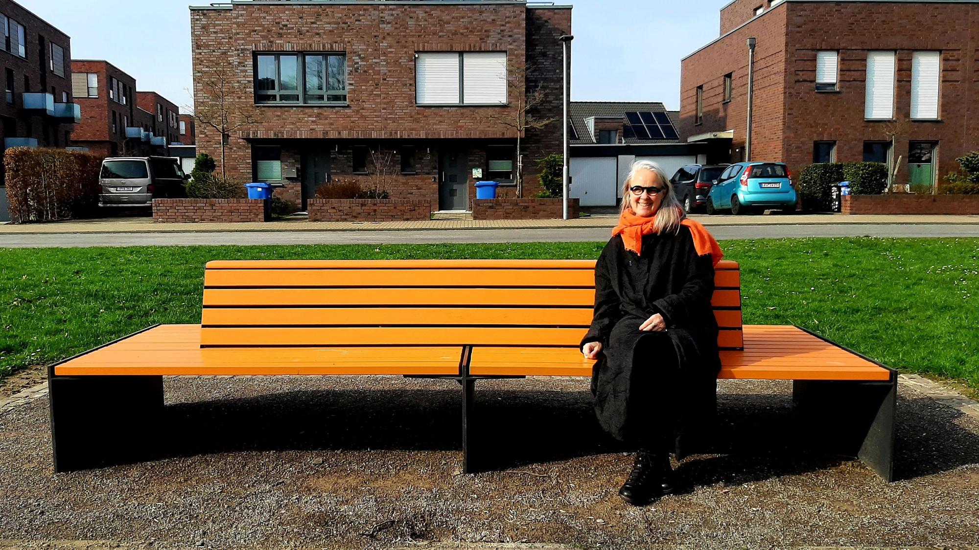 Susanne Wedewer vom Zonta-Club Leverkusen sitzt auf der vom Zonta-Club aufgestellten orangenen Bank in der Neuen Bahnstadt Opladen, auf der sie demnächst regelmäßig (bekannte) Menschen der Stadt zum Thema Frauenrechte, Gleichstellung, Sexismus, Gewalt gegen Frauen befragen will.