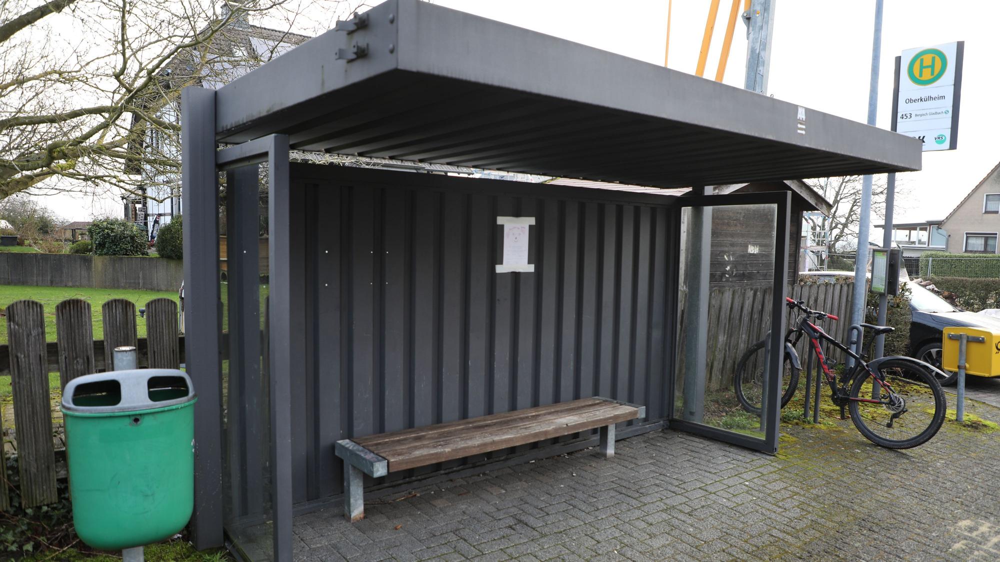 Die Bushaltestelle „Oberkühlheim“ in Bergisch Gladbach mitsamt Mülleimer links, Fahrradständer und Briefkasten rechts. Die Haltestelle bietet eine Sitzbank und einen Fahrplan.