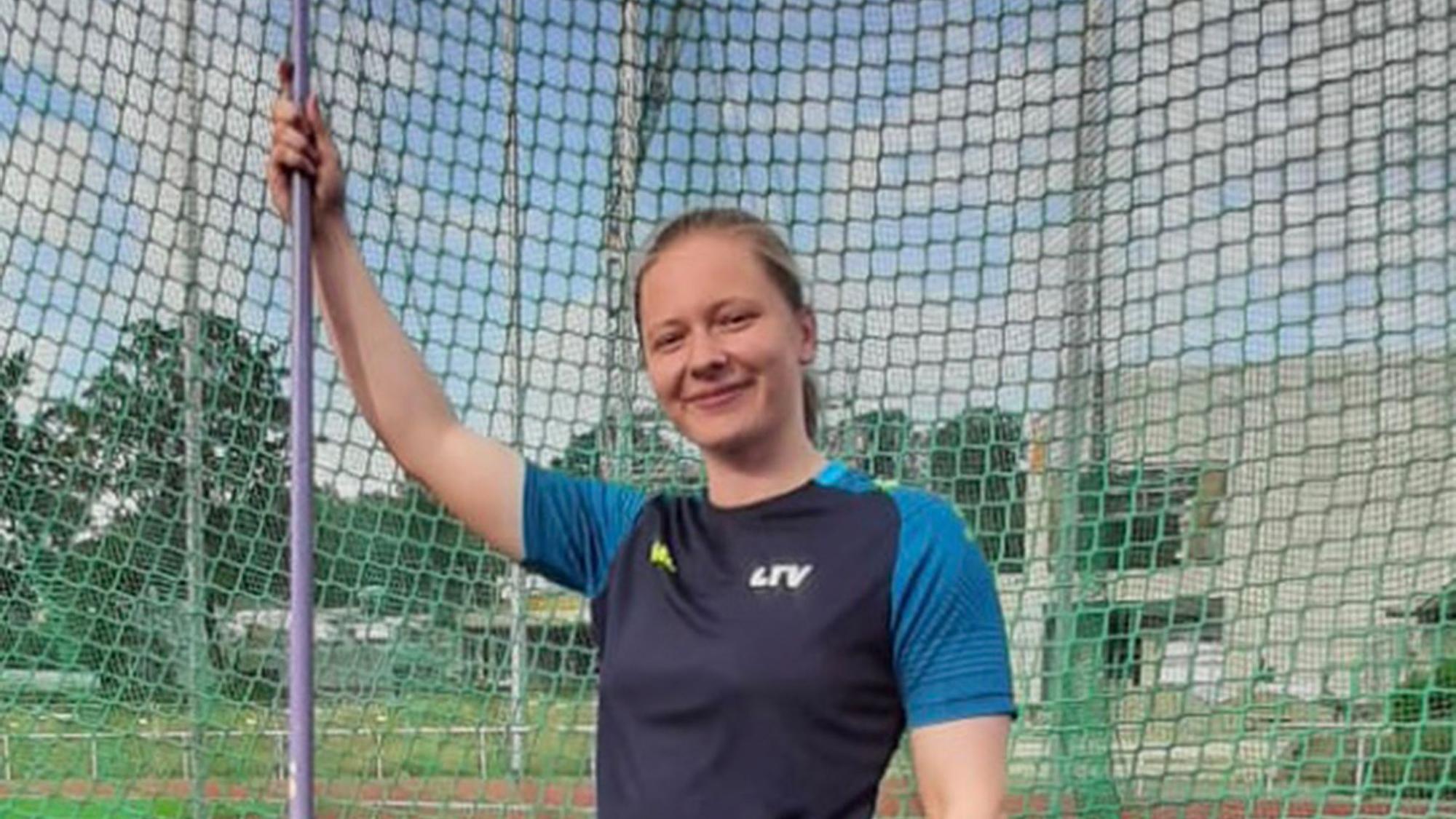 Victoria Krause hält einen Speer in der Hand und lächelt in die Kamera.