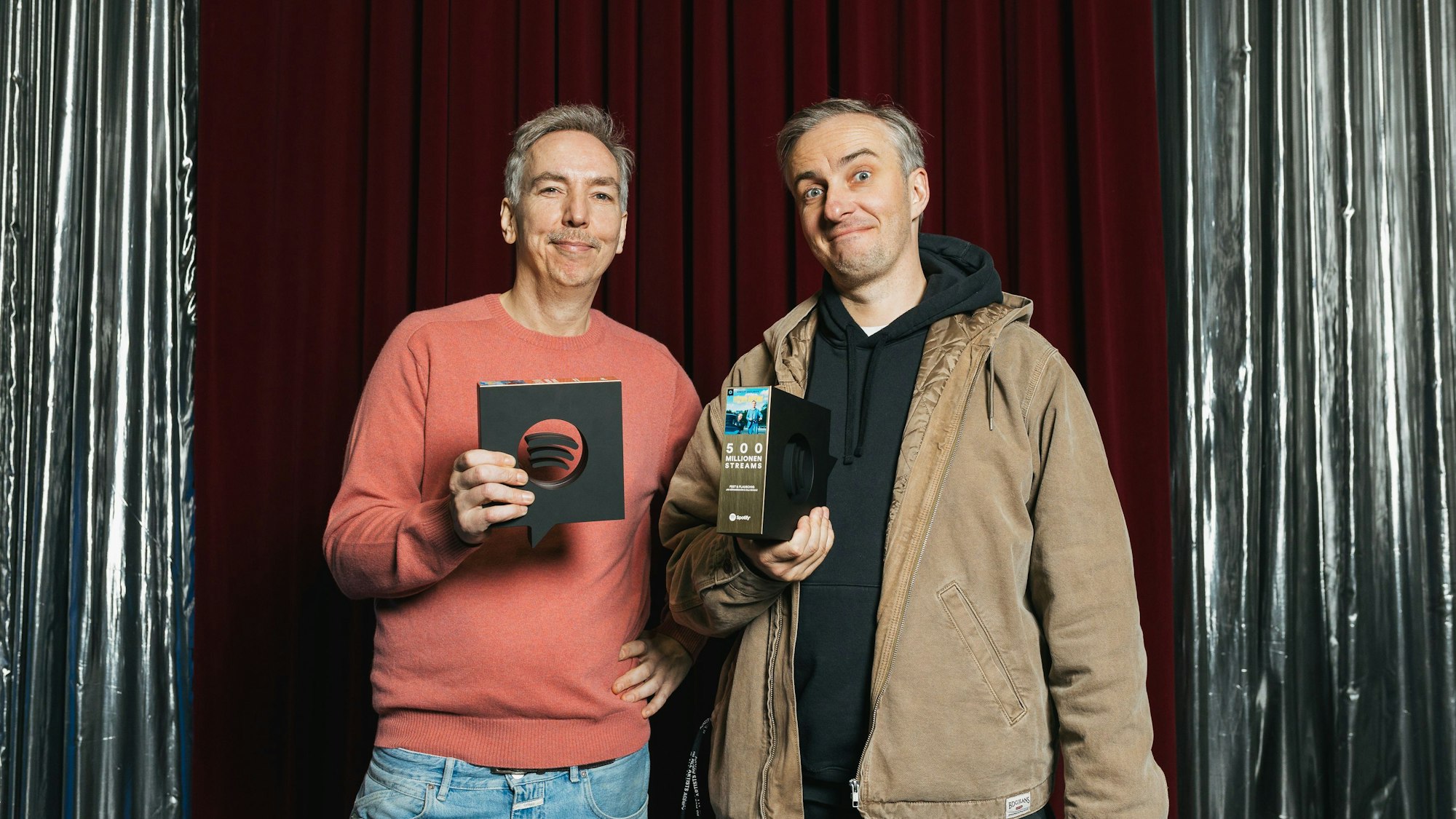 Die beiden halten den Preis in Form des Spotify Logos in die Kamera.