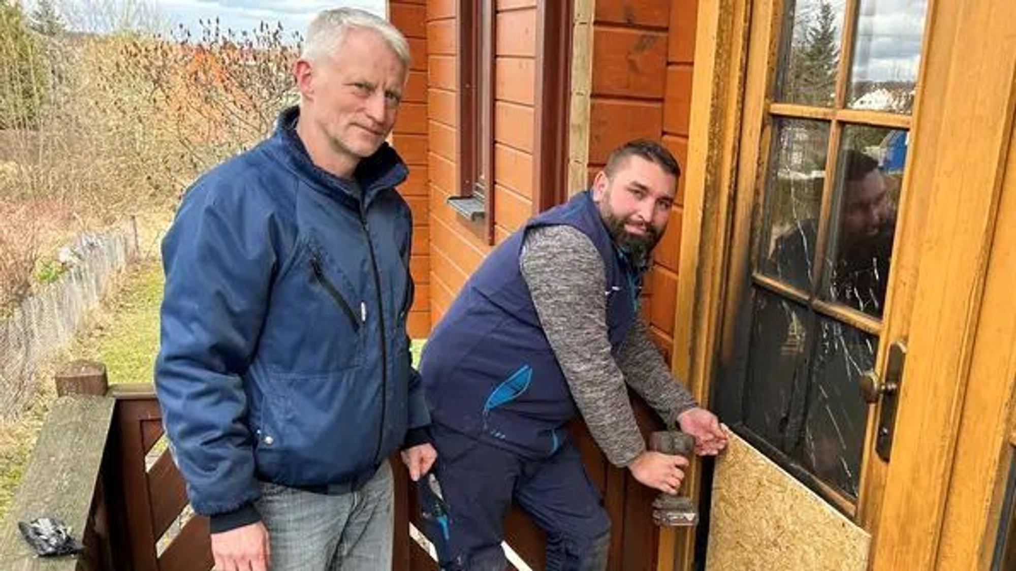 Die Spanplatte muss vorläufig die verkohlte Tür ersetzen: Kommunalpolitiker Michael Müller (links) mit dem SPD-Ortsvereinsvorsitzenden Andreas Hellmund.