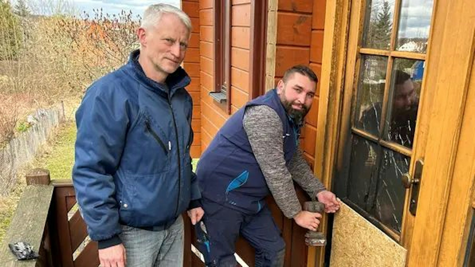 Die Spanplatte muss vorläufig die verkohlte Tür ersetzen: Kommunalpolitiker Michael Müller (links) mit dem SPD-Ortsvereinsvorsitzenden Andreas Hellmund.