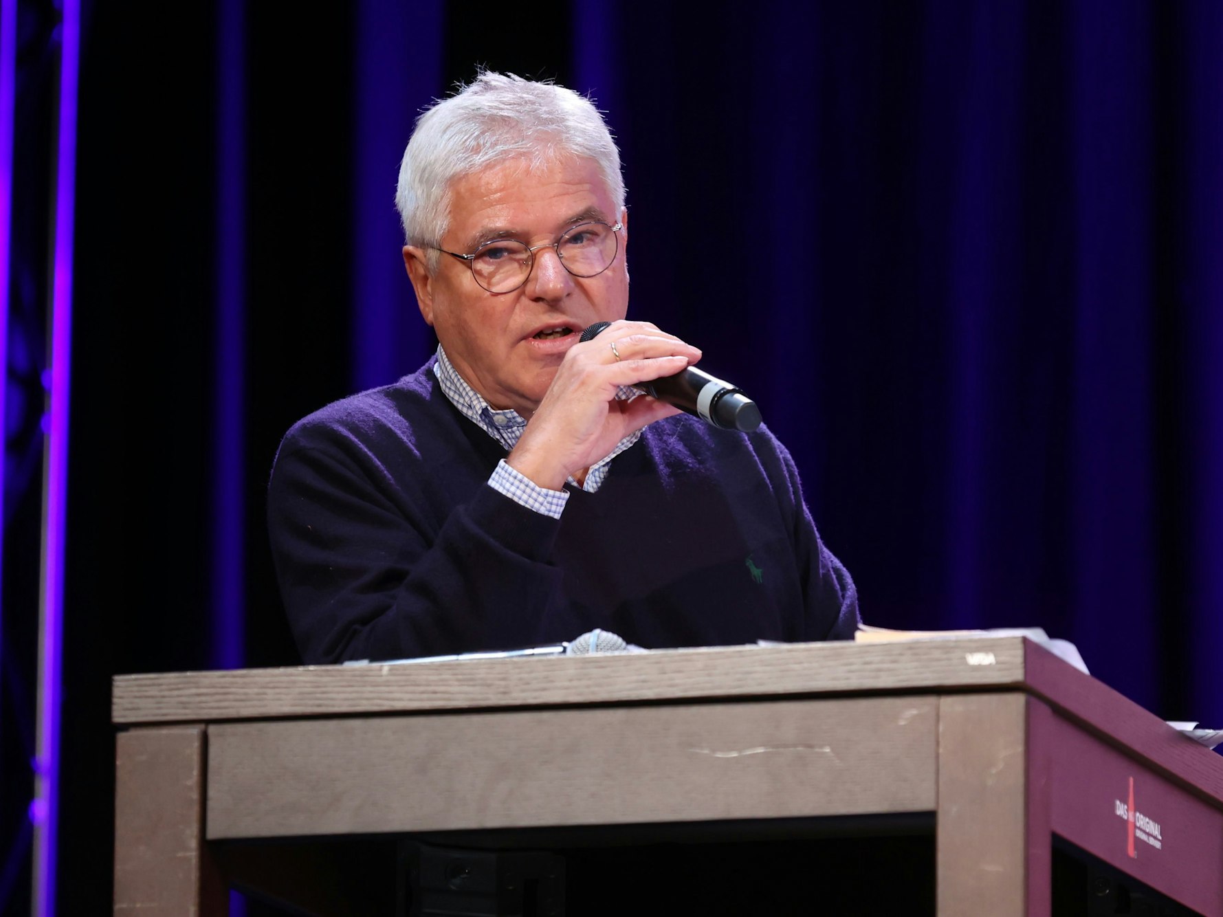 Axel Molinski, Geschäftsführer der Volksbühne am Rudolfplatz, steht an einem Rednerpult und spricht in ein Mikrofon.