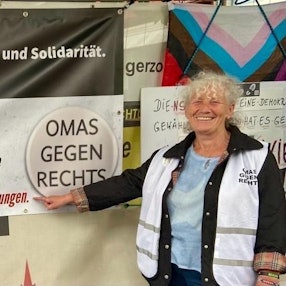 Walli Forner vor einem Plakat der Bürgerinitiative „Omas gegen Rechts“.