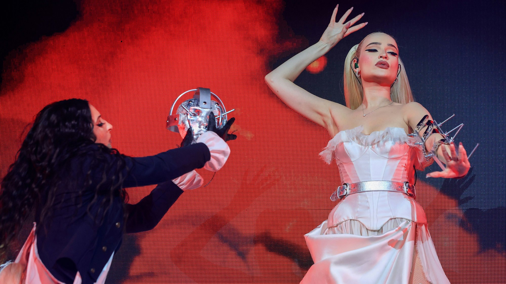 27.02.2024, Köln: Konzert Kim Petras im Palladium.
Eine Tänzerin hat der in Bonn geborenen Sängerin eine silberne Maske abgenommen. Petras posiert mit angewinkeltem Arm.