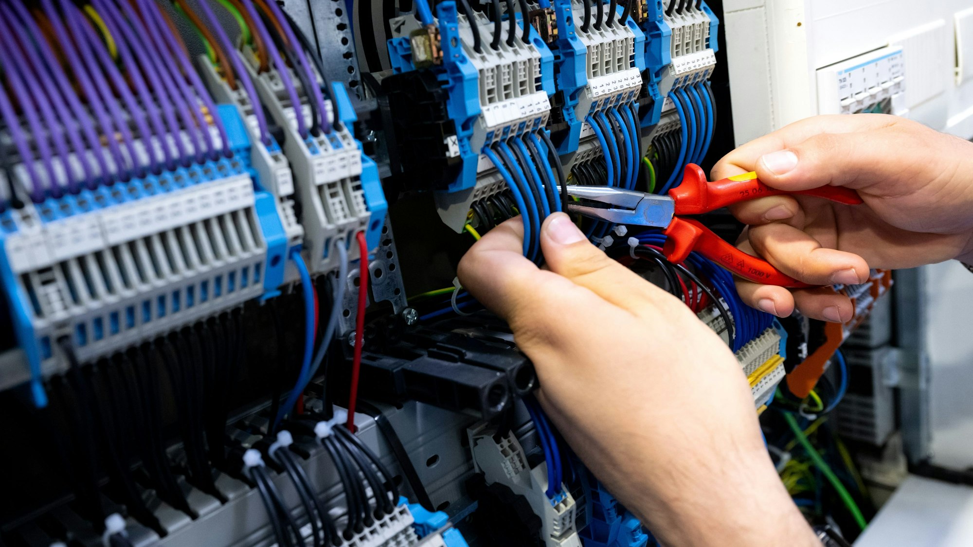 Ein Mann arbeitet bei einem Rundgang über die Internationale Handwerksmesse (IHM) an einem Messestand an einem Stromkasten.