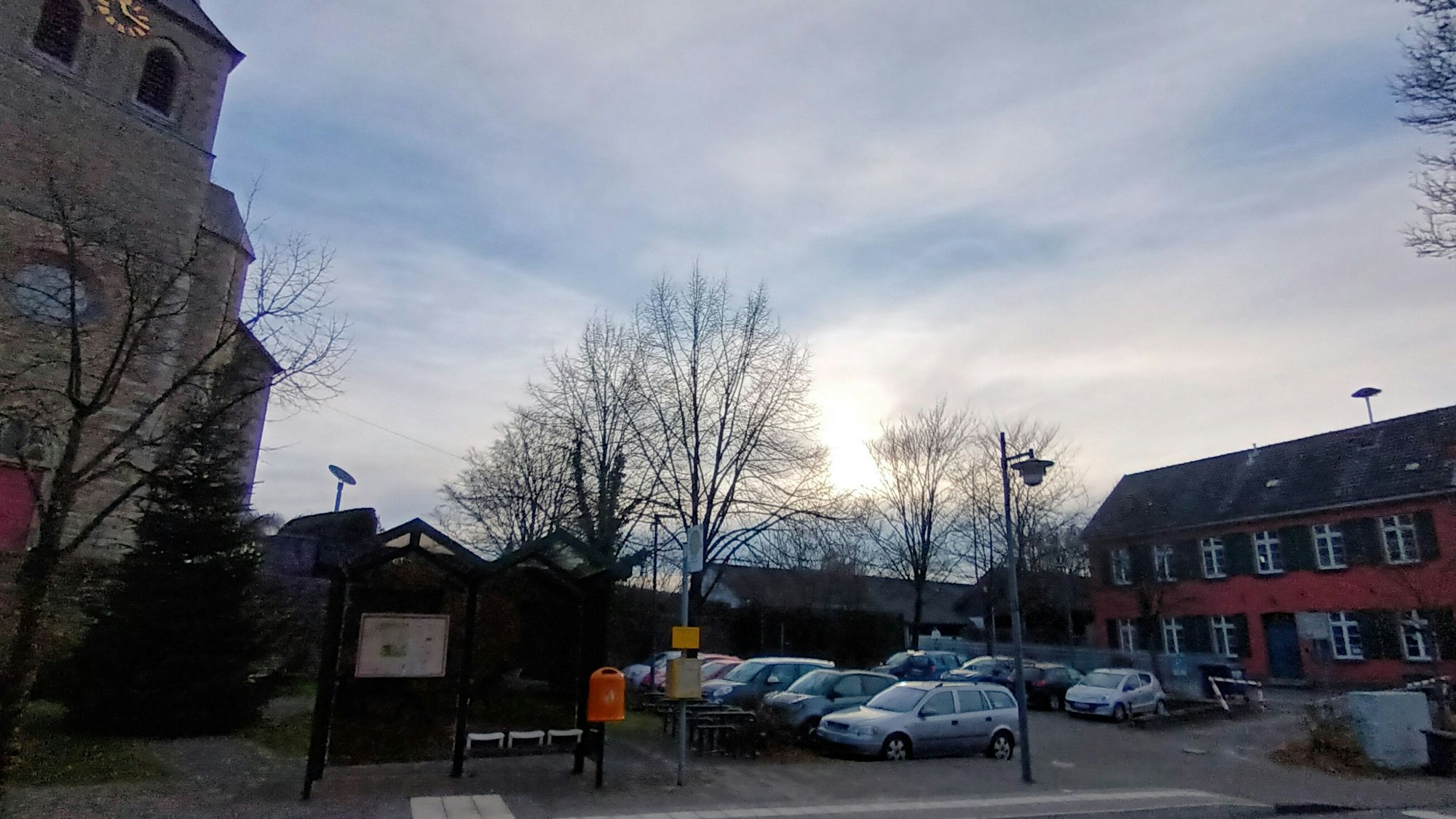 Eine Kirche und ein altes Gebäude, dazwischen ein Parkplatz