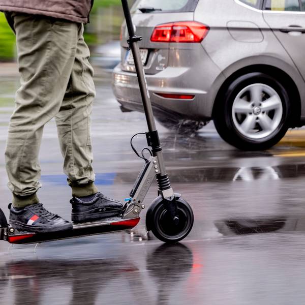 Ein Mann fährt mit einem E-Scooter auf der Straße.