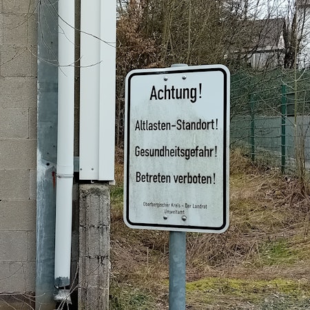 Ein Schild warnt „vor Gesundheitsgefahr!“.