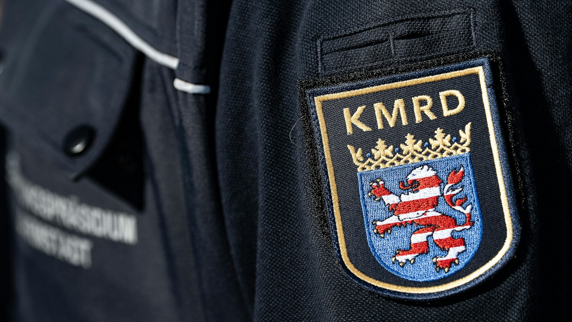 Das Wappen und das Logo vom Kampfmittelräumdienst ist auf einer Dienstkleidung zu sehen.