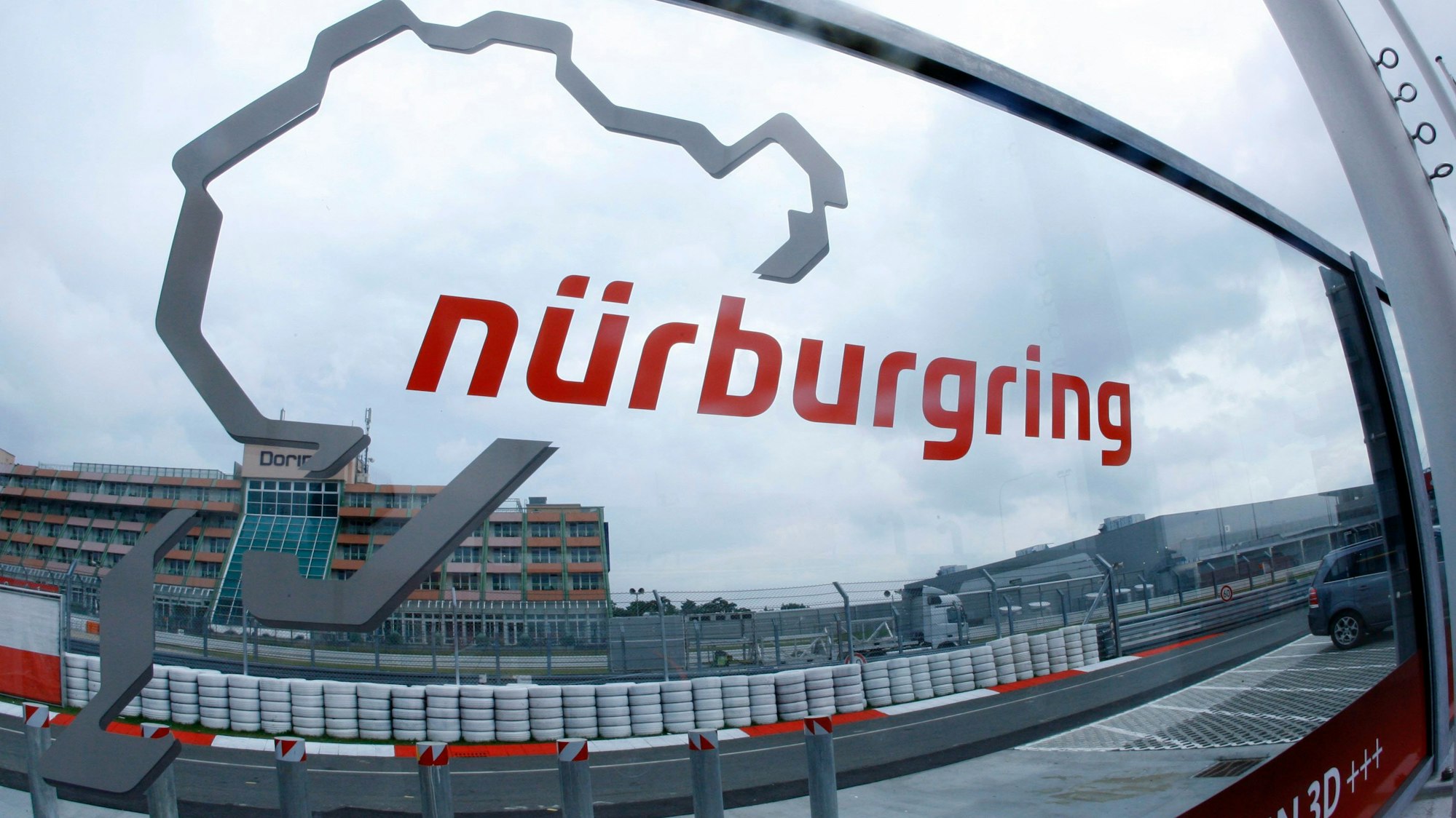 ARCHIV - 20.07.2011, Rheinland-Pfalz, Nürburg: Eine Glasscheibe mit dem Logo der Rennstrecke Nürburgring steht an der Zufahrt zur Rennstrecke Nürburgring. (zu dpa: «Mann verschanzt sich in Gebäude am Nürburgring - größerer Einsatz») Foto: Jens Büttner/dpa +++ dpa-Bildfunk +++