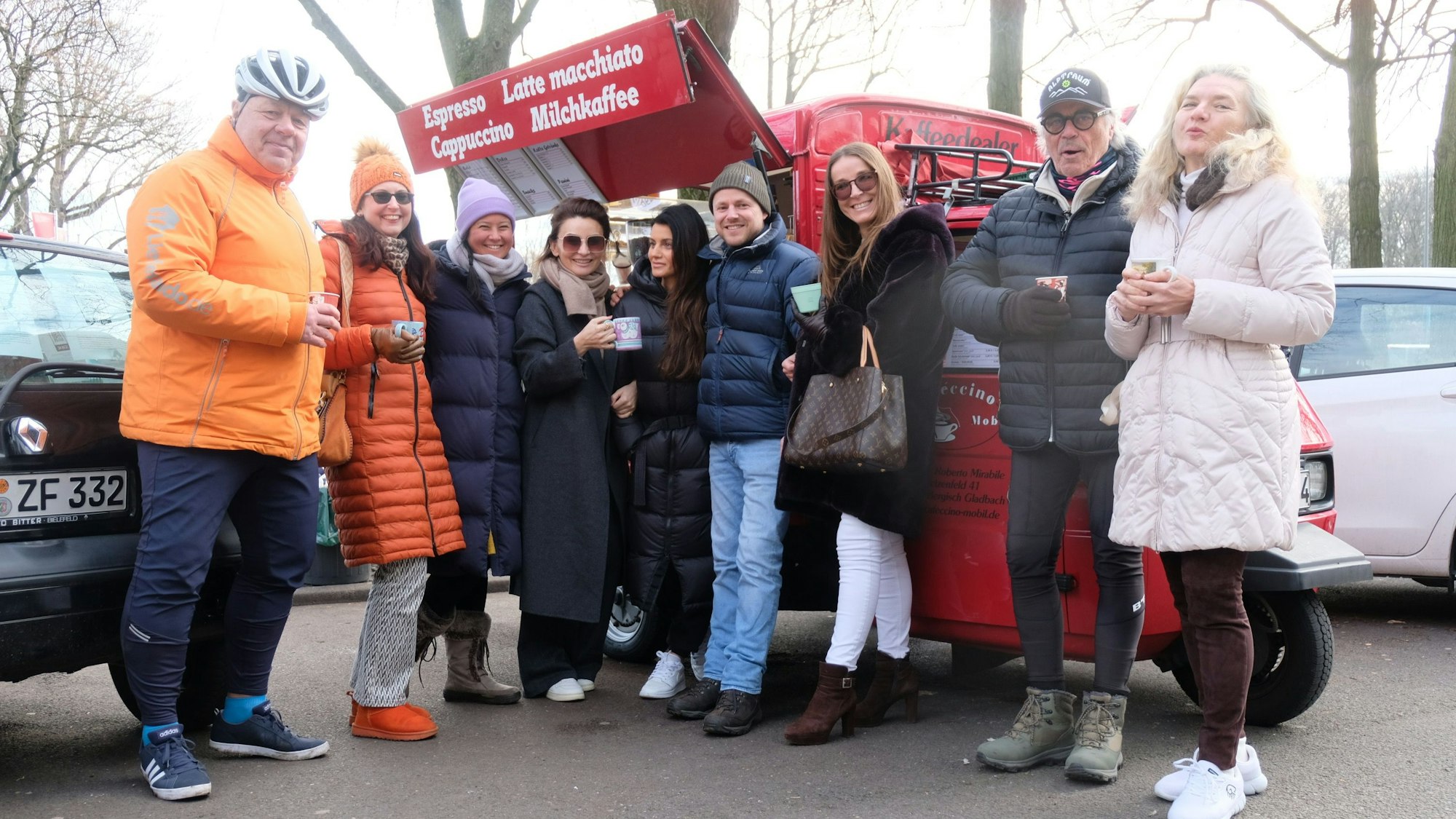 Vor dem roten Kaffee-Mobil von Roberto Mirabile stehen acht Kunden und Kundinnen mit Kaffeebechern in der Hand. Sie haben sich für ein Abschiedsfoto um den Eigentümer gruppiert. Die Stadt Köln hat ihm die Parkgenehmigung auf dem Parkplatz des Italienischen Kulturinstituts überraschend entzogen.