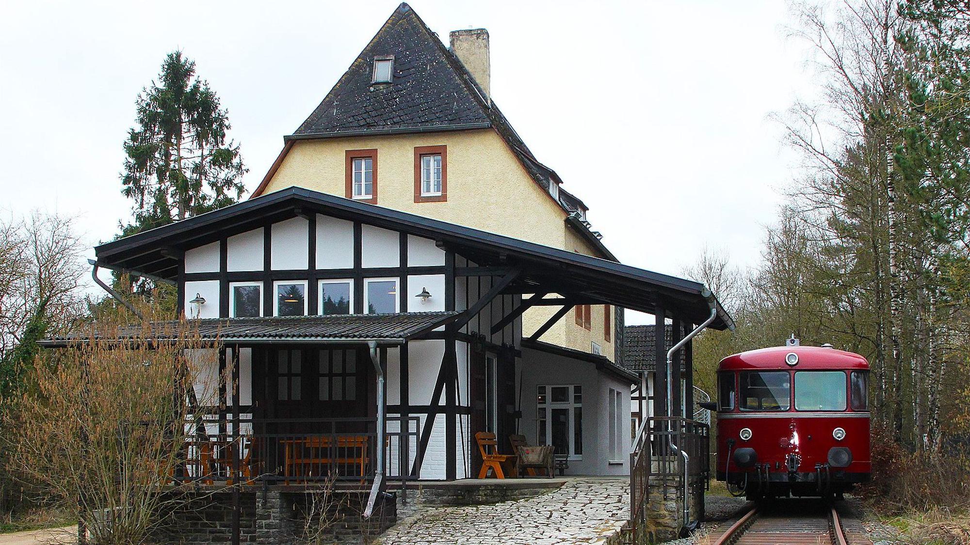 Neben dem Gebäude des Museumsbanhnhofs steht ein roter Schienenbus auf den Gleisen.