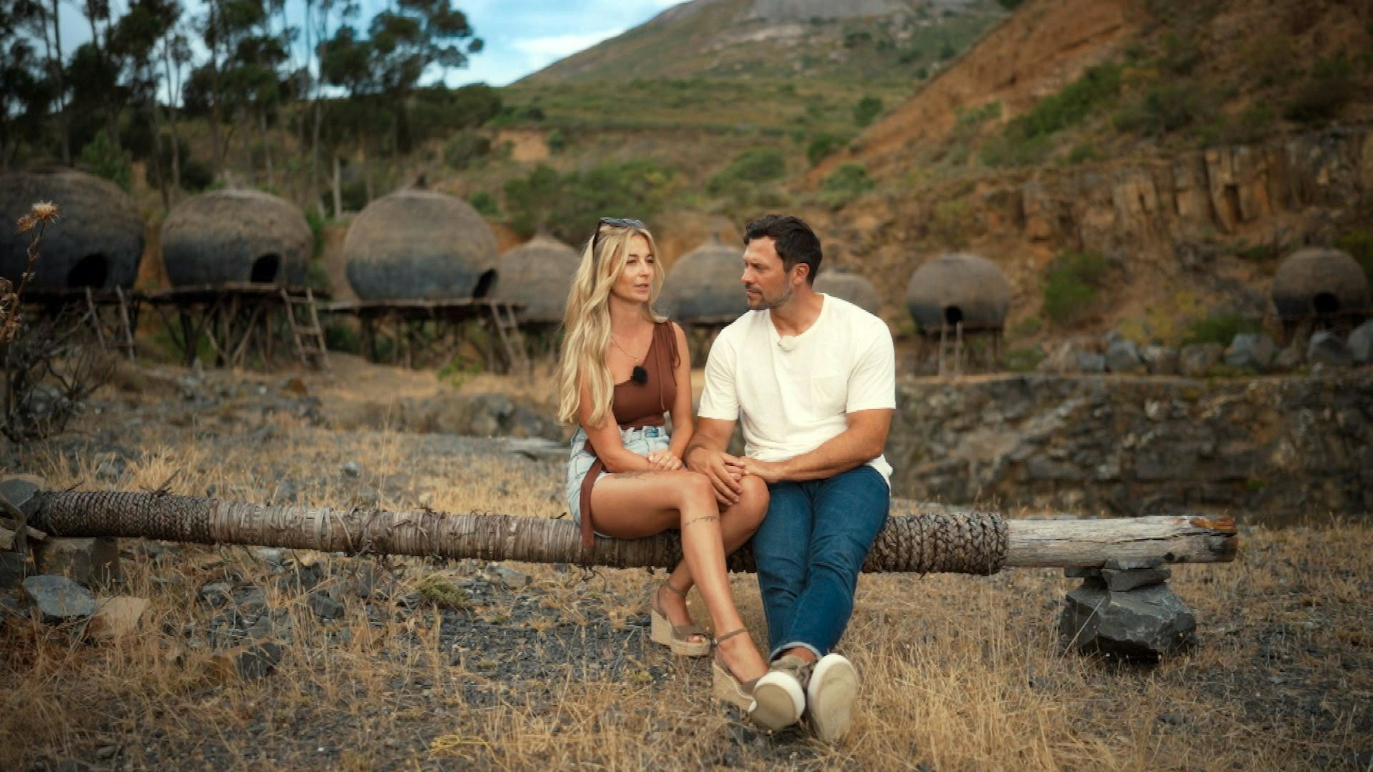 Larissa und Sebastian sitzen auf einem Baumstamm.
