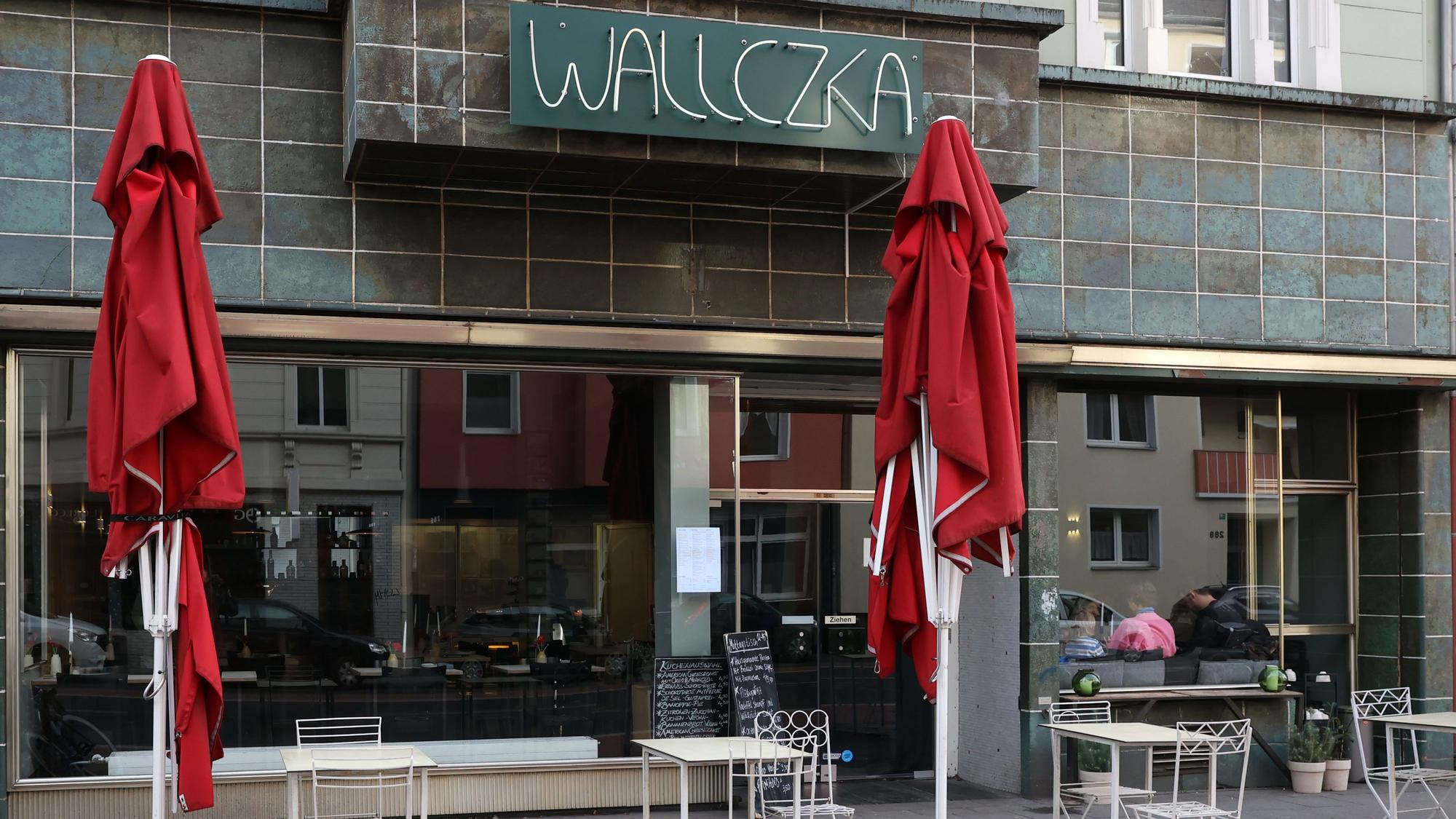 Das Restaurant Wallczka in Ehrenfeld mit Plätzen draußen und roten Sonnenschirmen.