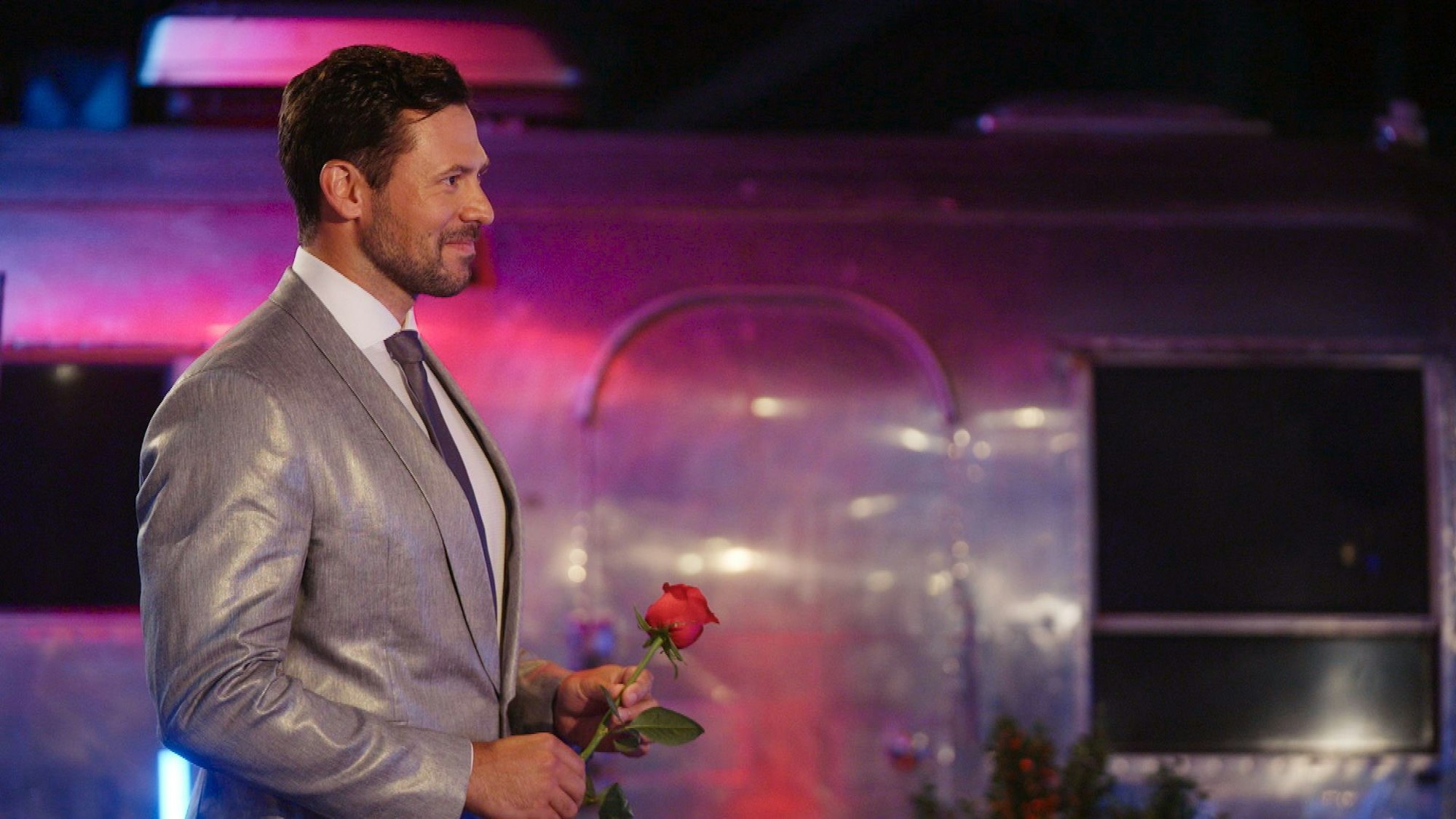 Sebastian trägt einen silbernen Anzug und hält eine Rose in der Hand.