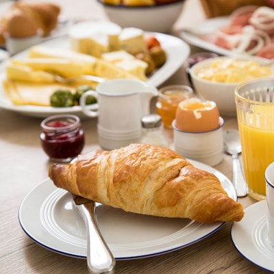 Ein Frühstückstisch mit Kaffee, Orangensaft, einem hartgekochten Ei und verschiedenem Aufschnitt. (Symbolbild)