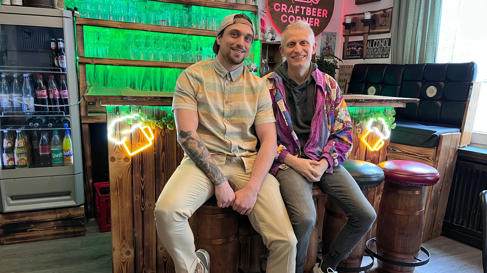 Zwei Männer sitzen in einer Kneipe auf Barhockern