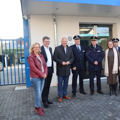 Frauen, Männer und Polizisten stehen vor einem Gebäude.