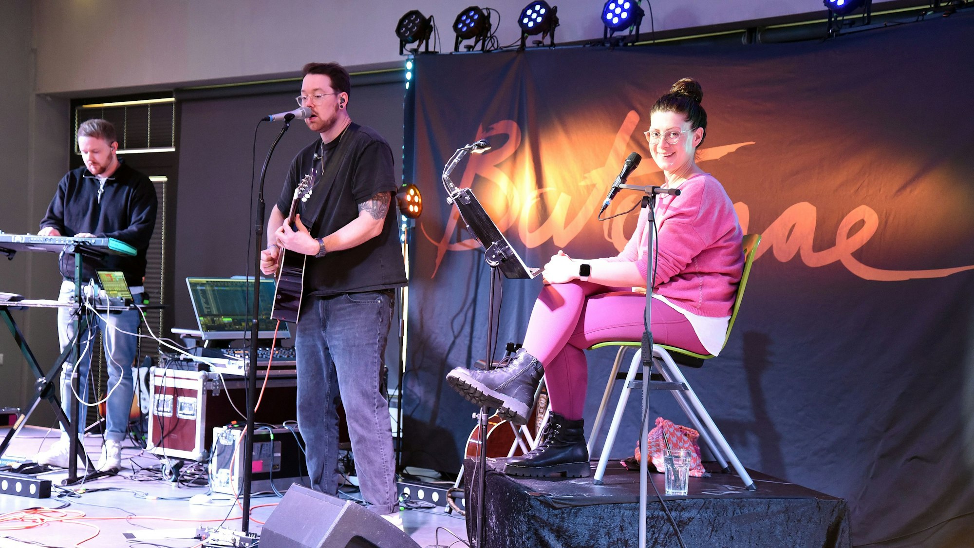 Bloggerin Jana Craemer (links) und die Musiker von Bartomae auf der Bühne im Aggertal-Gymnasium in Engelskirchen.