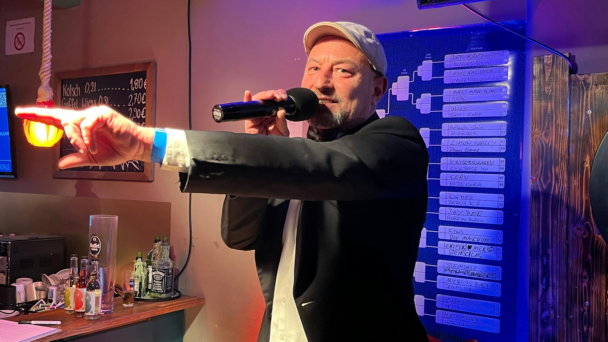 Muharrem Sahin steht als Organisator auf der Bühne. Sein ganzes Team trägt in Boxkampf-Manier schwarzes Jackett und Fliege.