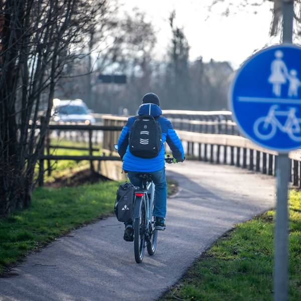 Das Bild zeigt einen Radfahrer, der offenbar mit dem Rad auf dem Weg zur Arbeit ist.