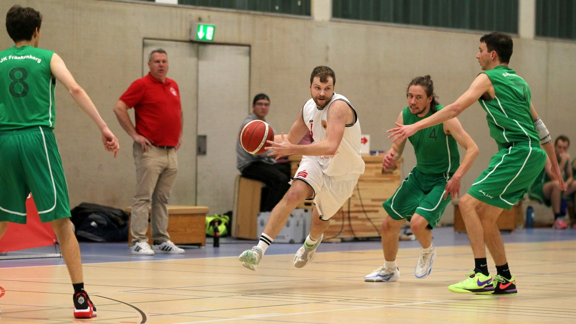 Basketballer Philipp Greuel läuft mit dem Ball, um ihn herum sind drei Gegenspieler.