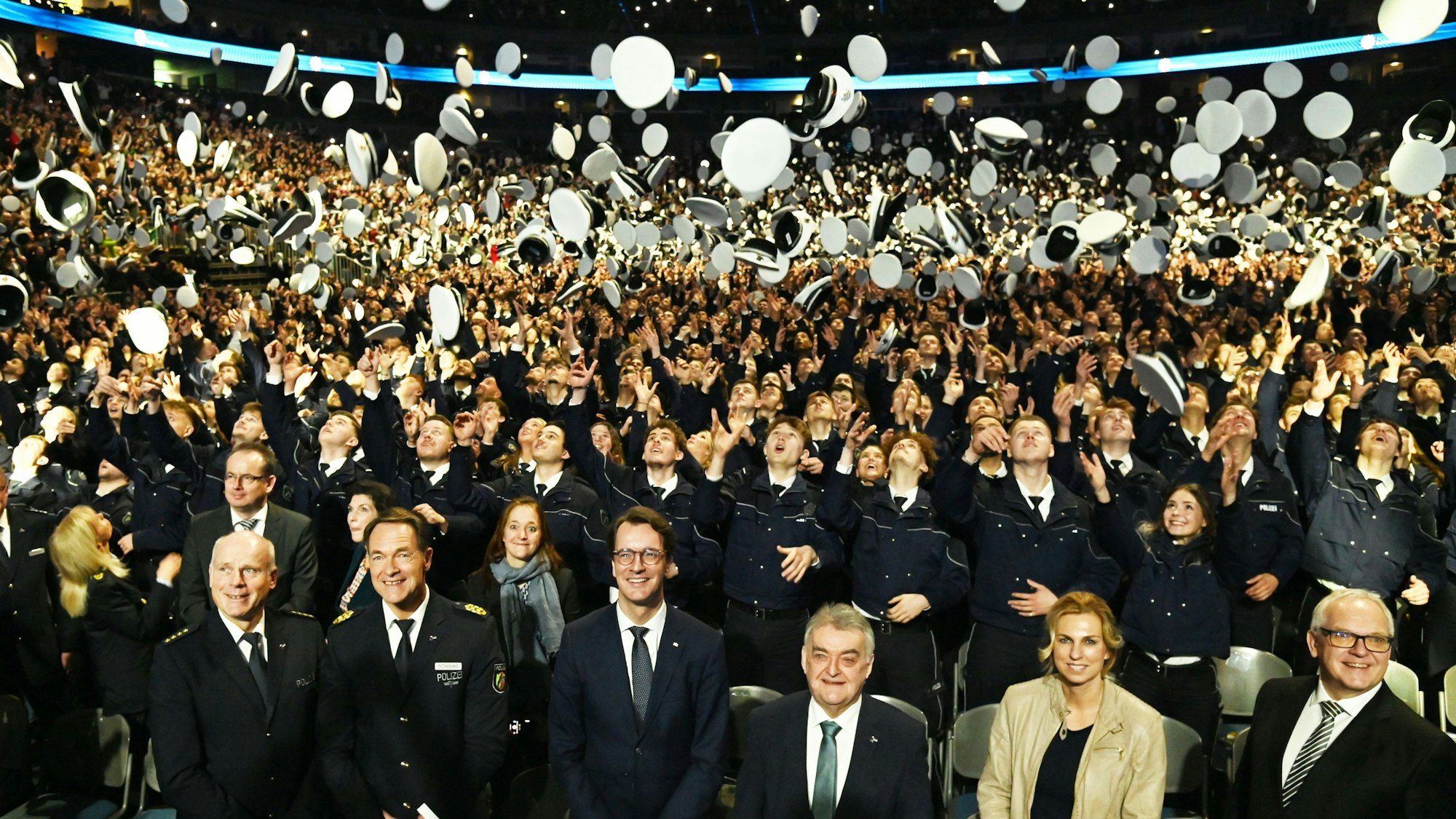Polizeianwärter in der Lanxess-Arena werfen ihren Hut in die Luft.