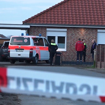 Einsatzkräfte stehen hinter einem Absperrband. Die Polizei ermittelt nach Schüssen im Landkreis Rotenburg wegen möglicher Kapitaldelikte. Es gebe zwei Tatorte - einen in einem Einfamilienhaus in Westervesede in der Gemeinde Scheeßel, außerdem in Bothel im Landkreis Rotenburg.