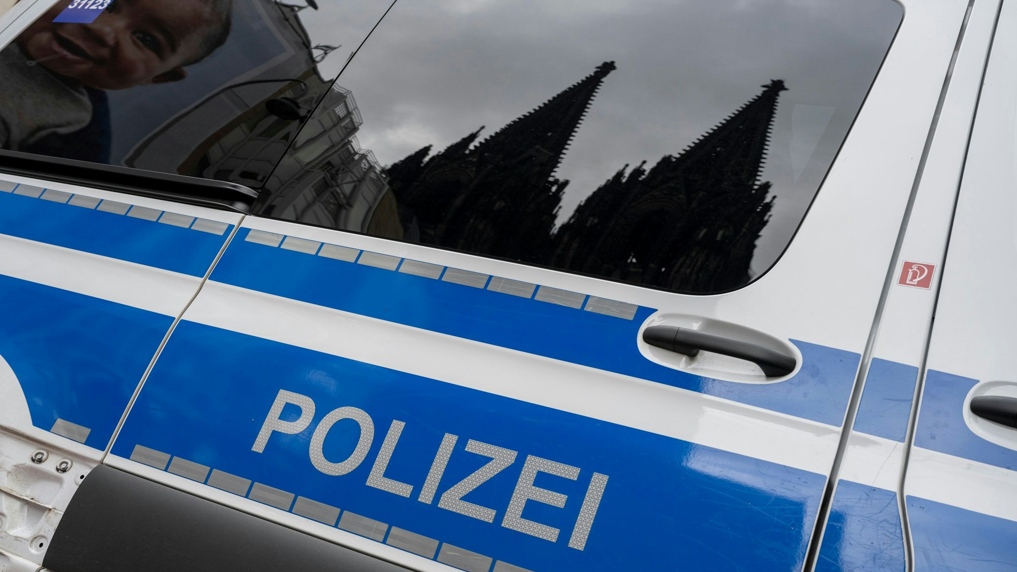 Der Dom spiegelt sich in den Fenstern eines Polizeiautos.
