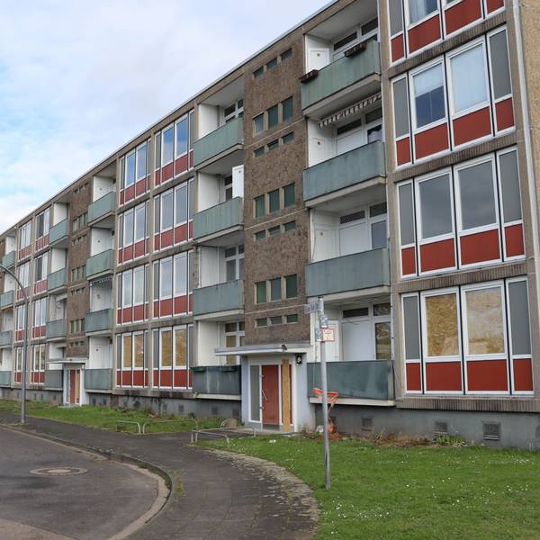 Blick auf ein vierstöckiges, verwahrlostes Wohngebäude