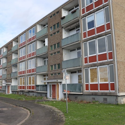 Blick auf ein vierstöckiges, verwahrlostes Wohngebäude