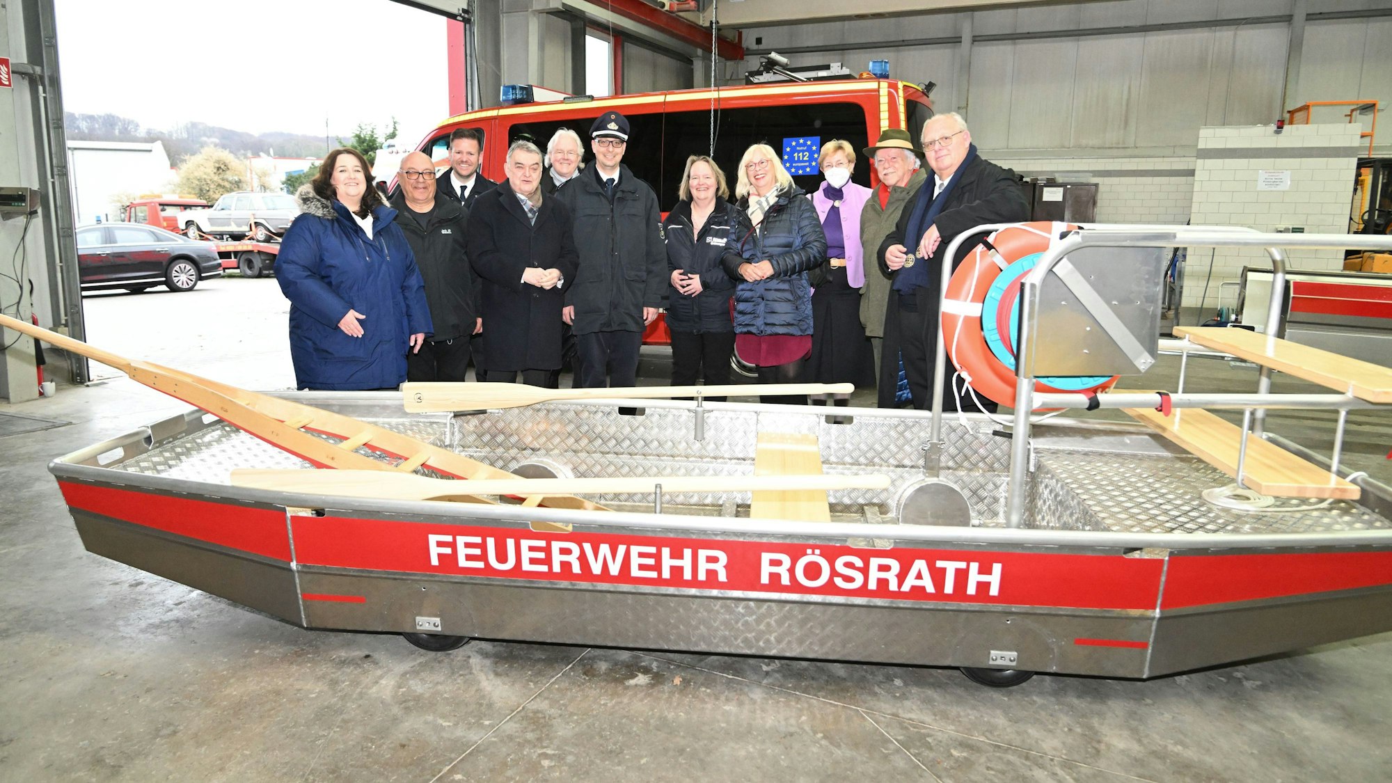 Menschen stehen hinter einem neuen Boot für die Rösrather Feuerwehr.