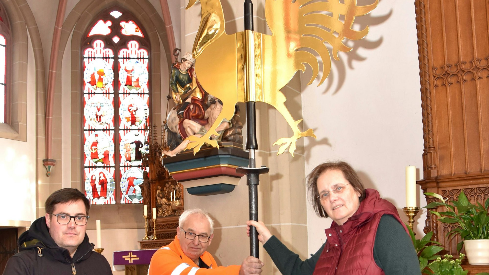 Zu sehen sind Stefan Schüll, Walter Kamp und Monika Schüll, die den goldenen Wetterhahn halten.