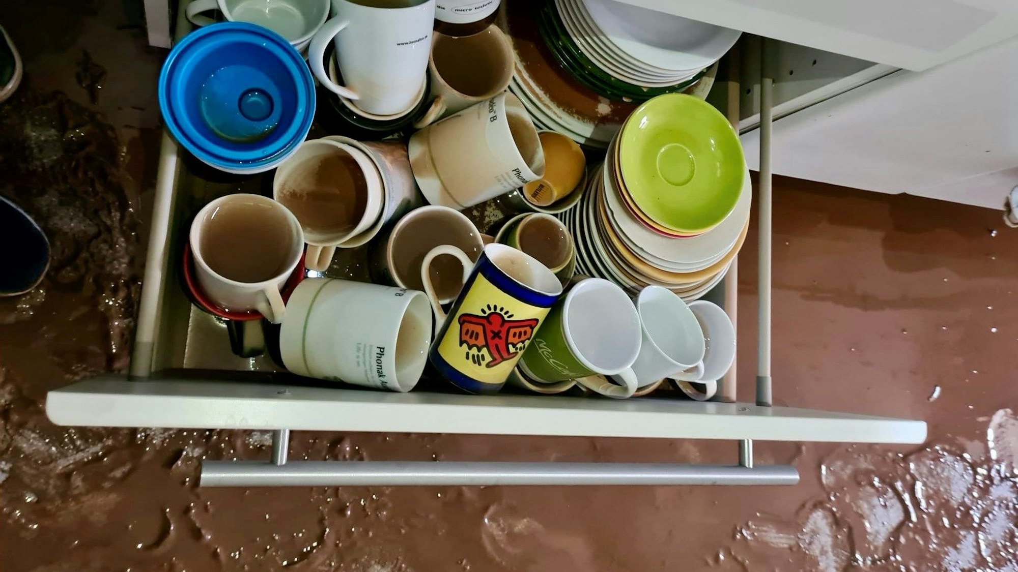 Eine halb mit Wasser vollgelaufene Schublade mit Tassen