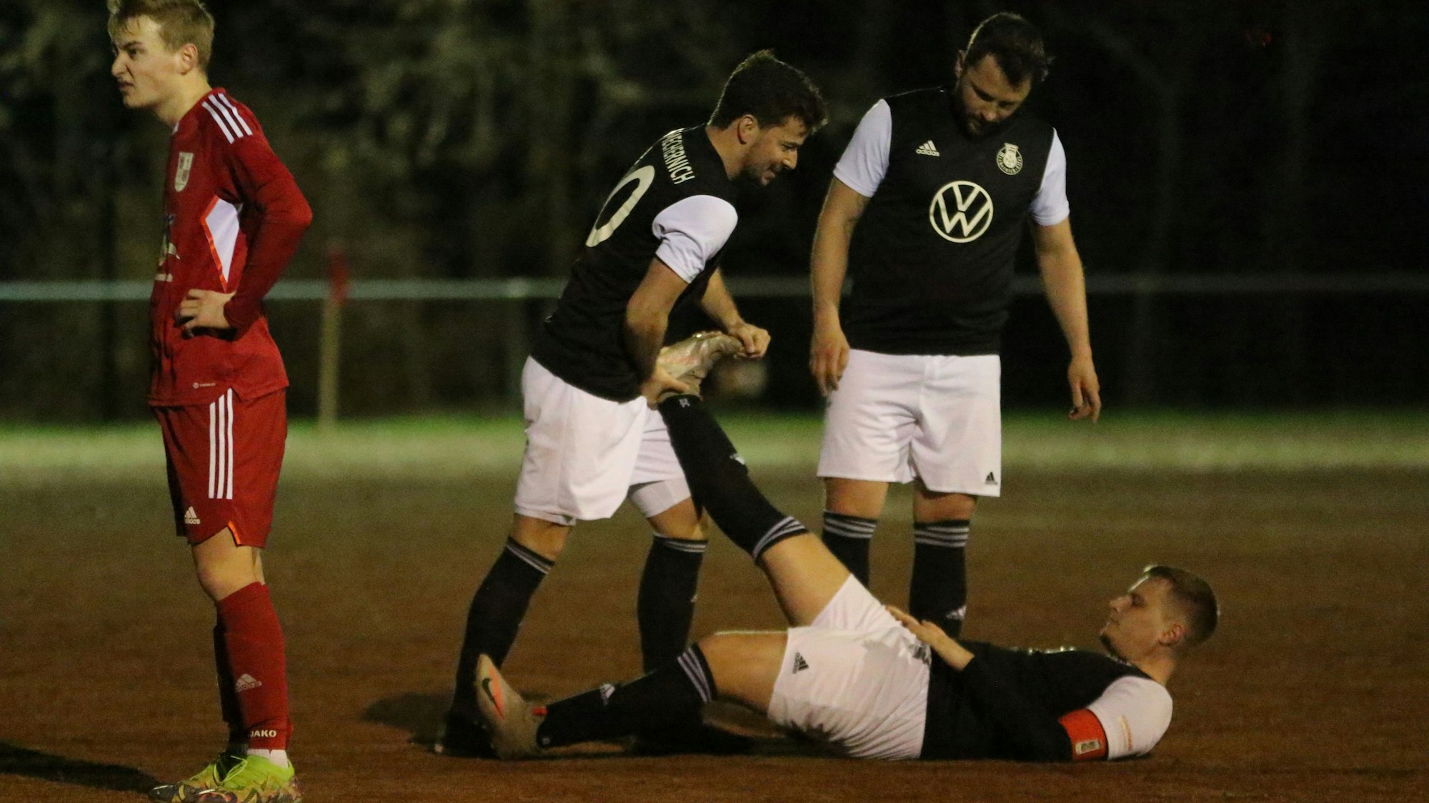 Mechernichs Andre Beaujean liegt mit einem Krampf auf dem Boden. Ein Mitspieler hilft ihm.
