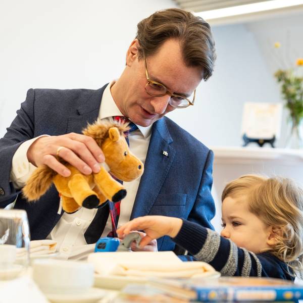 Hendrik Wüst (CDU, li), Ministerpräsident von Nordrhein-Westfalen, spielt am Tisch mit seinem Ehrenpatenkind Daniel.