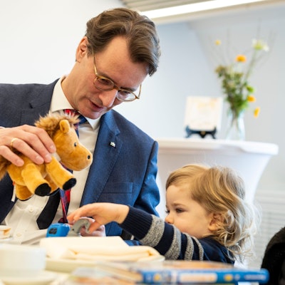 Hendrik Wüst (CDU, li), Ministerpräsident von Nordrhein-Westfalen, spielt am Tisch mit seinem Ehrenpatenkind Daniel.
