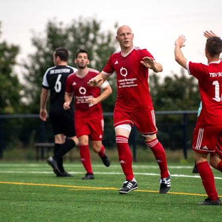 Das Bild zeigt Sven Gräbe, wie er mit einem Teamkollegen abklatscht.
