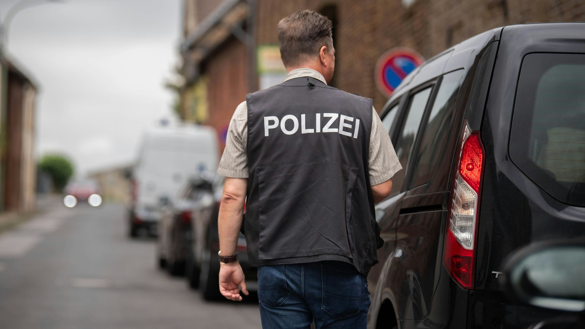 Nach einem brutalen Überfall in Zülpich-Füssenich geht ein Ermittler, der eine Weste mit der Aufschrift „Polizei“ trägt, zu einem Haus.